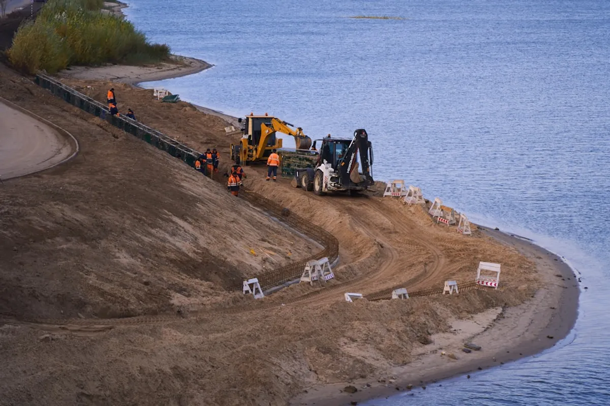 Road embankment with rock bag stabilization, excavator on shoulder